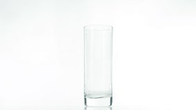Pouring Milk from a jug into a glass isolated on a white background, a natural dairy product in a transparent glass is spinning on a white background