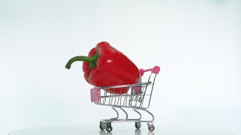Natural vegetable bell pepper in a trolley from a supermarket is spinning on a revolving table, appetizing red pepper is spinning on a table on a white background