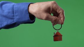 Hand dangling house icon key ring on green screen chroma key background,  - Powered by Shutterstock - Get 15% off with code: PIKWIZARD15