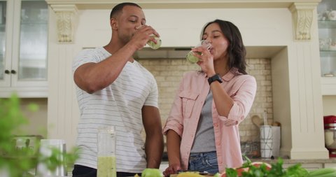 Happy biracial couple drinking self-made smoothie in kitchen. healthy lifestyle and enjoying quality leisure time at home.