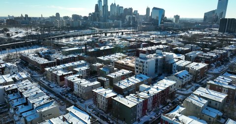 Urban city residential housing homes covered in winter snow. American city skyline in distance.