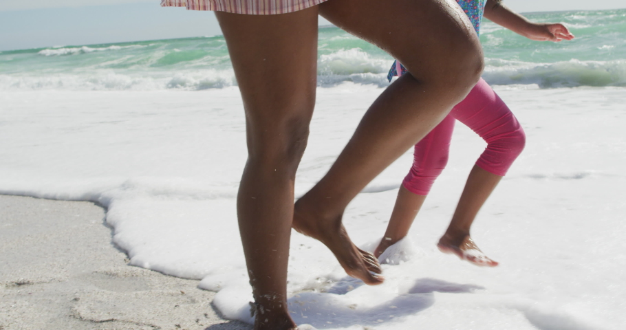 Midsection of happy hispanic moter with daughter and son walking on beach. family holidays, free time and togetherness.