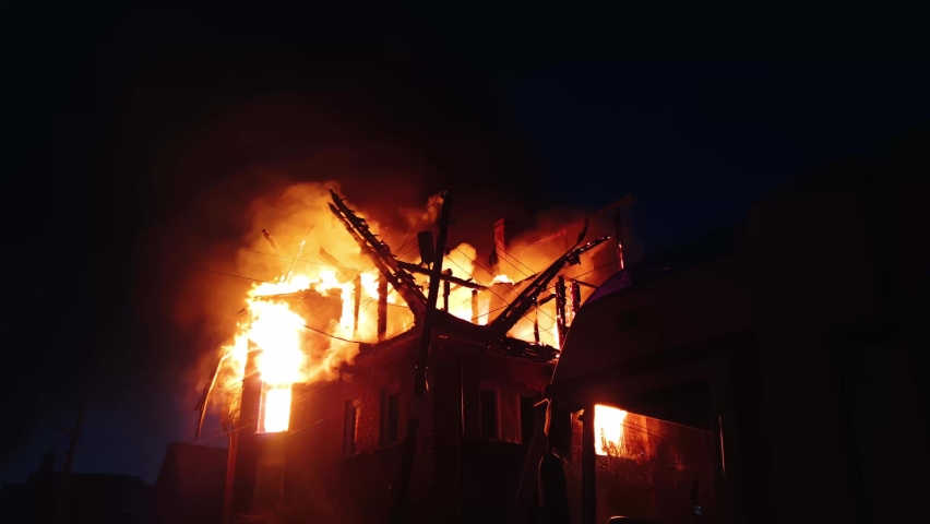 The roof of the house is on fire. The residential building burn, village. Firefighters put out a fire. Fire Department putting out flame. Fire truck, headlights and panel, siren, signal, alarm. Royalty-Free Stock Footage #1086868673