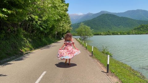 Inspired runaway alone romantic boho chic girl in long dress runs along road along river overlooking the mountains