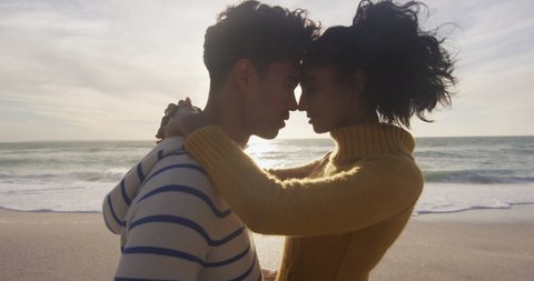 Portrait of hispanic couple standing and embracing on beach. holidays, relaxation, outdoor lifestyle and togetherness.