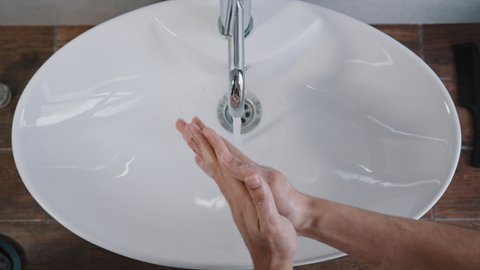 Close-up male hands washing in large white sink at home in bathroom in hotel daily hygiene body care man wash hand treatment washes palms cleans bacteria coronavirus outbreak prevention in hotel room
