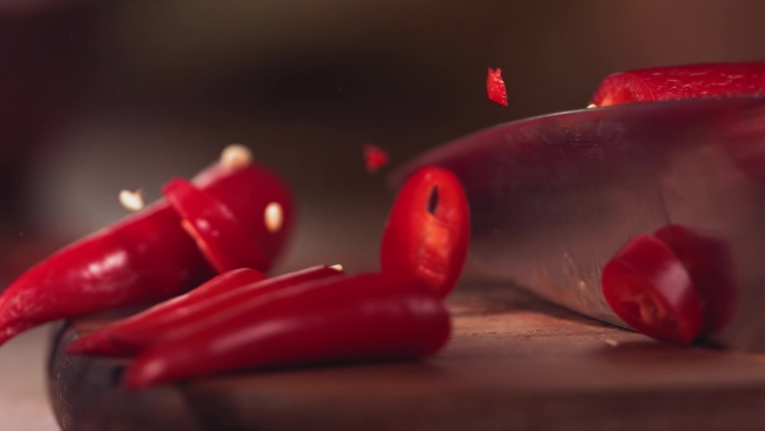 Knife Cutting Red Chilli Pepper on Wood in Slow Motion