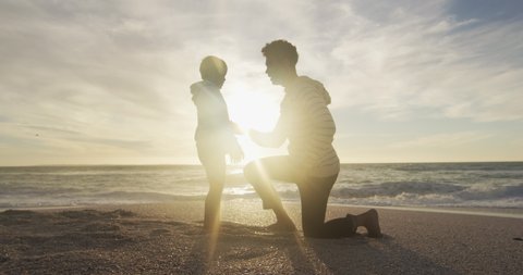 Hispanic father embracing son on beach at sunset. family holidays, free time, togetherness and spending time outdoors.