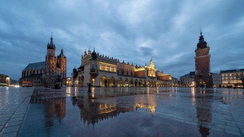 4k time lapse of Krakow main square with reflections of St mary's basilica and the cloth hall  during rainy sunrise