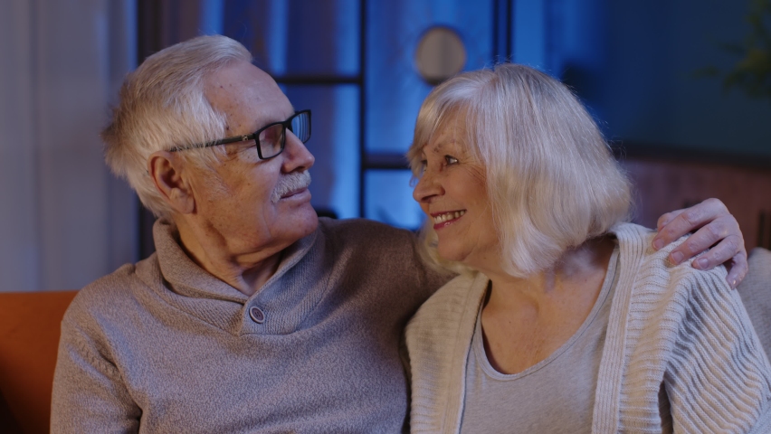 Happy old senior elderly family couple hugging, laughing, smiling looking at camera, healthy retired two grandparents husband wife. Grandmother grandfather embracing sitting on sofa at home, portrait Royalty-Free Stock Footage #1086872573