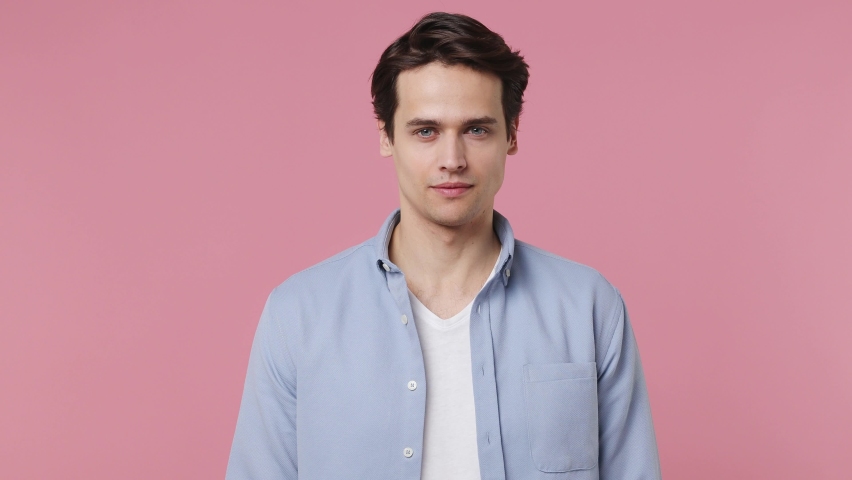 Happy blithesome charismatic fascinating fun young brunet man 20s years old wears blue shirt looking camera smiling isolated on plain pink background studio portrait. People emotions lifestyle concept Royalty-Free Stock Footage #1086876110