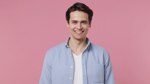 Happy blithesome charismatic fascinating fun young brunet man 20s years old wears blue shirt looking camera smiling isolated on plain pink background studio portrait. People emotions lifestyle concept