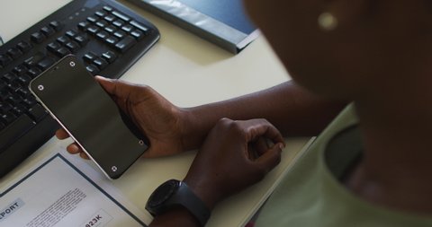 Hands of african american businesswoman holding smartphone with copy space on screen. independent creative business, working at a modern office.