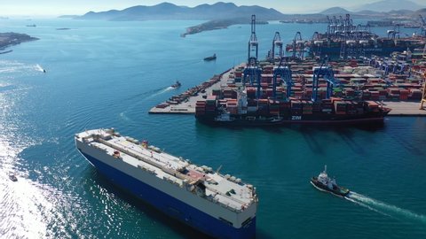 Perama, Attica - Greece - February 11 2022: Aerial drone video of industrial Ro Ro automobile carrier leaving logistics loading - unloading Terminal