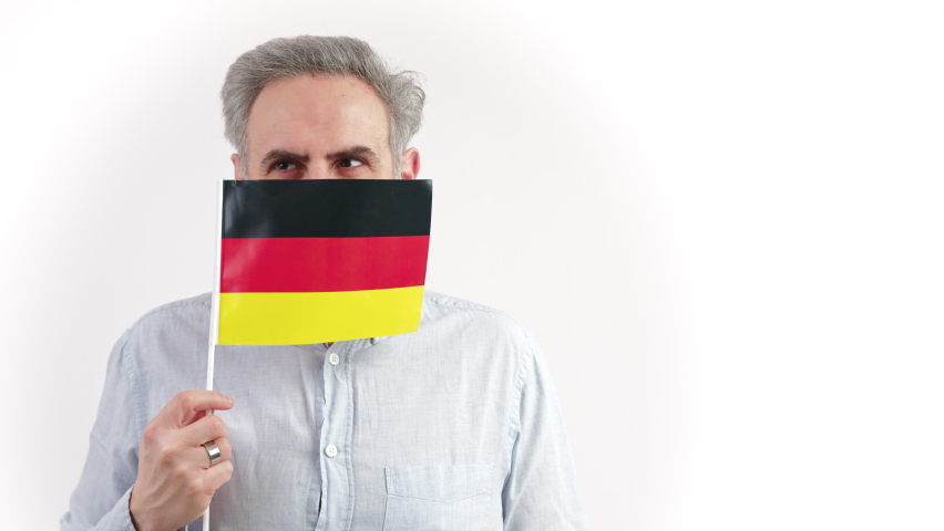 40s caucasian man hiding behing the Germany flag and looking around. High quality 4k footage