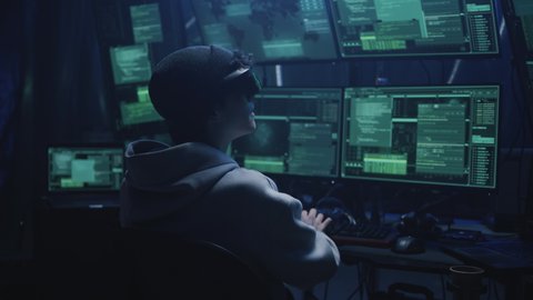 Hacker in virtual reality helmet in cyberspace located on secret hacker base with servers and multiple monitors during massive cyber attack. Trying to hack data or steal money in the meta universe