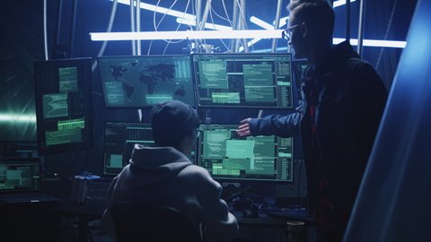 Group of hackers near monitors communicating nervously during cybercrime massive cyber attack. They quarrel and argue