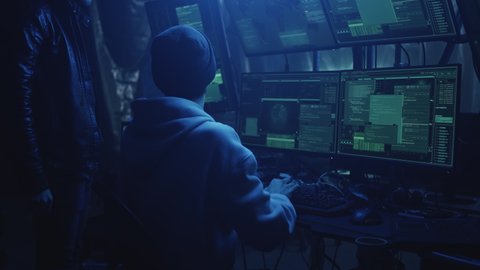 Young cybercriminals hacking documents on modern computer and making cyberattack on government in equipped hacker hideout