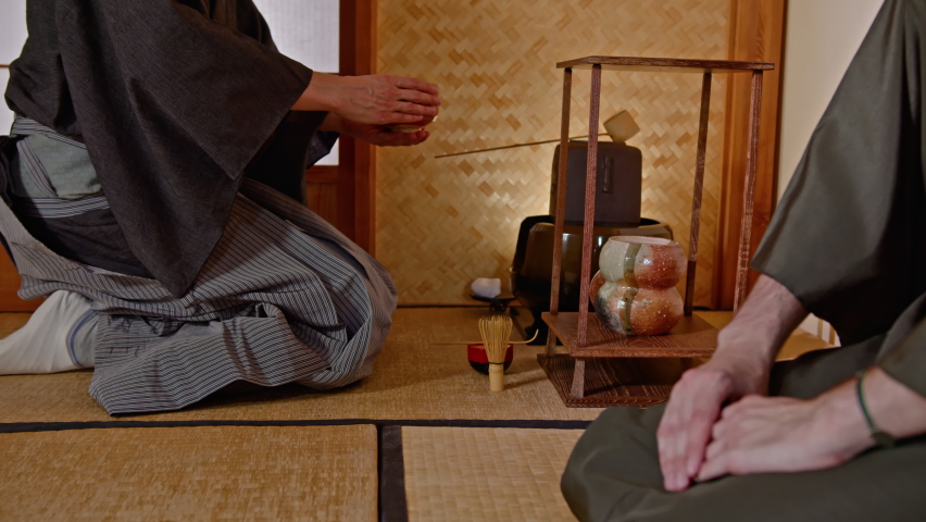 A scene from a Japanese tea ceremony. A tea master in traditional clothes has prepared a matcha drink and serves the guest a chawan in compliance with all the rituals. The National Treasure of Japan Royalty-Free Stock Footage #1086892559