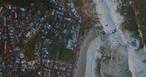 Aerial birds eye overhead top down view of rough sea waves rolling on coast in city. Cape Town, South Africa