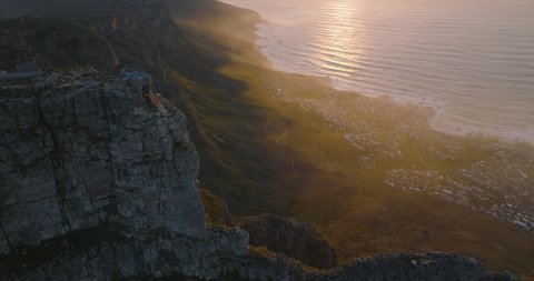 Breath taking landscape aerial scenery. Fly over Table Mountain summit, panoramic view on rock ridge and ocean coast against picturesque sunset. Cape Town, South Africa