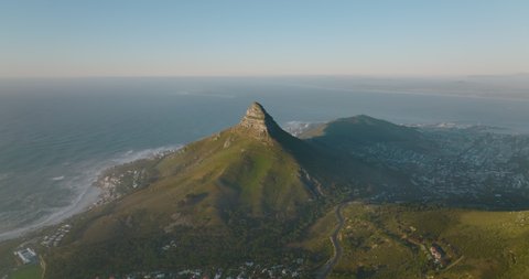 Elevated shot of pointed peak with steep slopes falling to suburb on one side and to sea coast on another. Cape Town, South Africa