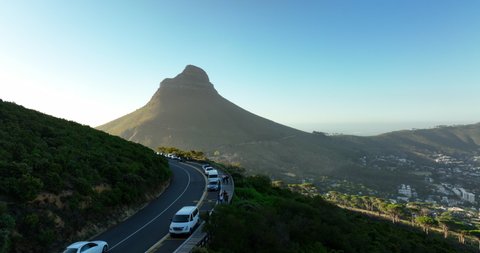 Amazing shot of Lions Head mountain towering above residential neighbourhoods of city. Cars parked along road. Cape Town, South Africa
