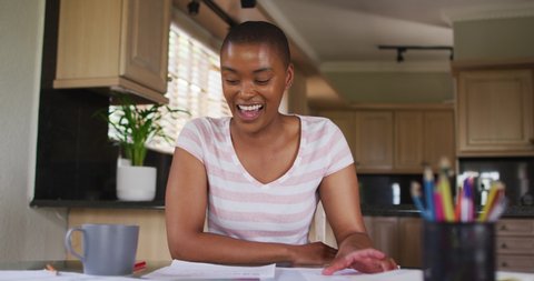 Happy african american woman gesturing and having video call in kitchen. technology and communication, flexible working from home.