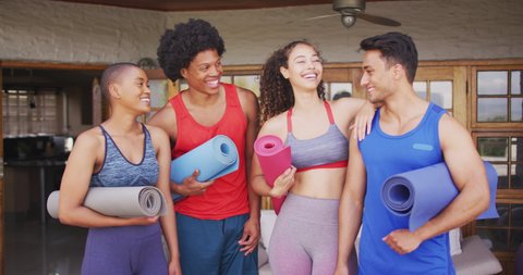 Group of diverse male and female friends holding yoga mats and laughing. healthy lifestyle and hanging out with friends at home and garden.