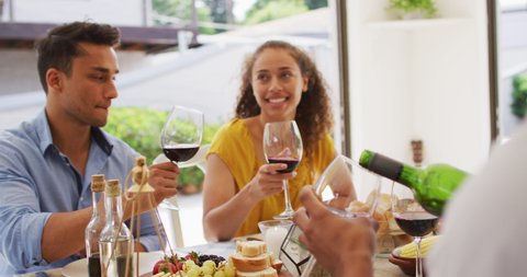 Two diverse male and female friends toasting with wine at dinner party on patio. hanging out with friends at home and garden.