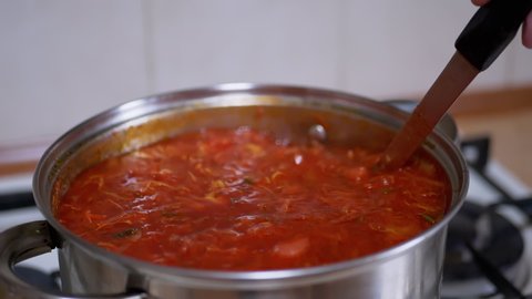 Preparing Rich, Thick, Red Borscht from Meat, Beet in a Saucepan in Home Kitchen. Vegetarian food made from vegetables, potatoes, carrots. Traditional, national food of Ukrainian and Russian cuisine.