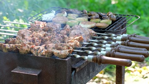 Shashlik barbecue. Kebab cooking outdoors on metal skewer. Marinated barbecue meat cooked at barbeque. Grilled pork, meat lamb, shish kebabs, shashlik. Street food popular in Europe, Russia