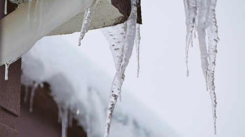 the ice on the roof is melting, the icicles are melting, the drops dripping from the icicles,