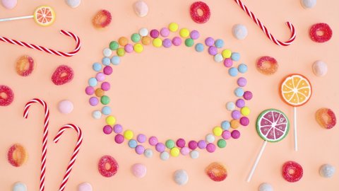 6k Candies and lollipops creative arrangement frame copy space on bright pastel orange background. Stop motion flat lay