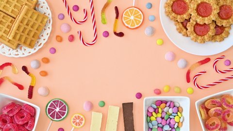 6k Creative frame copy space with sweet cookies, candies and lollipops move. Stop motion flat lay