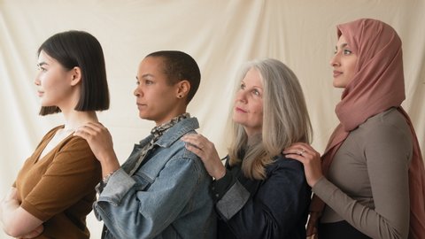 Slow motion side view of four women with hands on each other's shoulders in support of International Women's Day