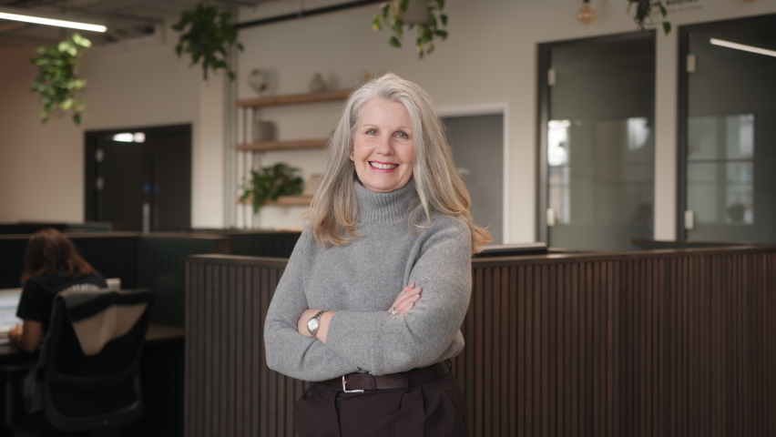 Slow motion of confident senior white woman with long grey hair smiling and looking at camera in coworking space | Shutterstock HD Video #1086912104
