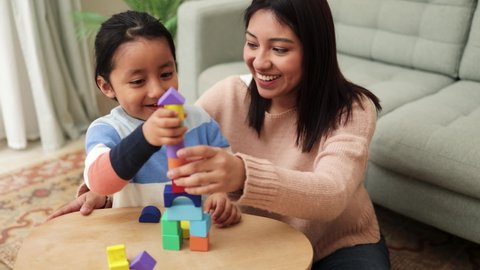 Latin mother and kid having fun playing didactic games at home - Family time together