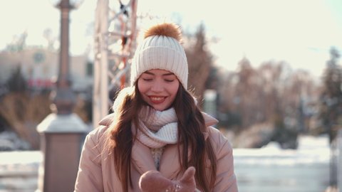 Young woman dressed winter jacket white knitted hat and scarf standing outdoor on winter city street Handheld effect. High quality 4k footage