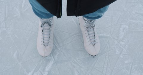 A girl in white figure skates on a skating rink. Concept of winter sports, hobbies, ice skating, engaged in outdoor sports, pastimes, healthy lifestyle