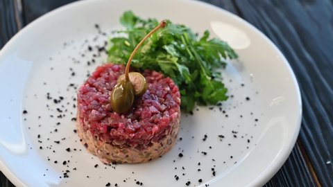 Fresh tuna tartare with capers and greens on white plate