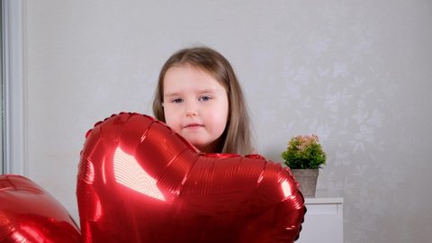 Pretty cute girl holding heart shaped crane balloons on valentines day.