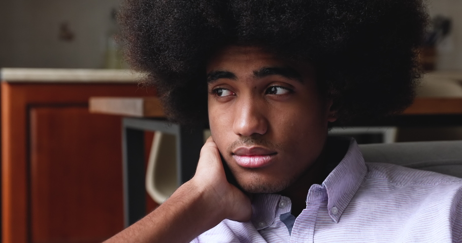 Close up face sad African teenage 18s guy sit at home alone, looks pensive thinks over life concerns or unrequited love, suffers from unfair situation. Teen relation problem, break up, worries concept | Shutterstock HD Video #1086926750