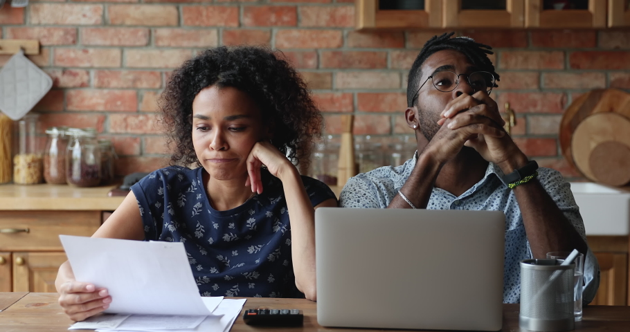 Worried African American couple engaged in home accountancy discuss debt financial problem overspending money from family budget. Confused young spouses calculate expenses troubled with overdue bills | Shutterstock HD Video #1086926801