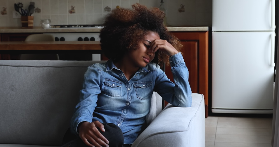 Teenage problems, insecure teen having life concerns, unplanned pregnancy and abortion decision concept. Upset African 20s girl deep in sad thoughts, thinks looks aside, feels stressed and unhappy