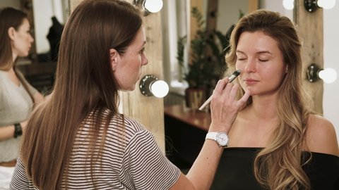Time-lapse video of professional make-up artist working process during makeup routine for young and beautiful model before photo shoot
