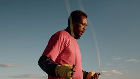 Black man boxer in sportswear and hands wrapped at bandages trains outdoors, jumps over skipping rope, side view. African-American male trains outdoors. Concept of training - Powered by Shutterstock - Get 15% off with code: PIKWIZARD15