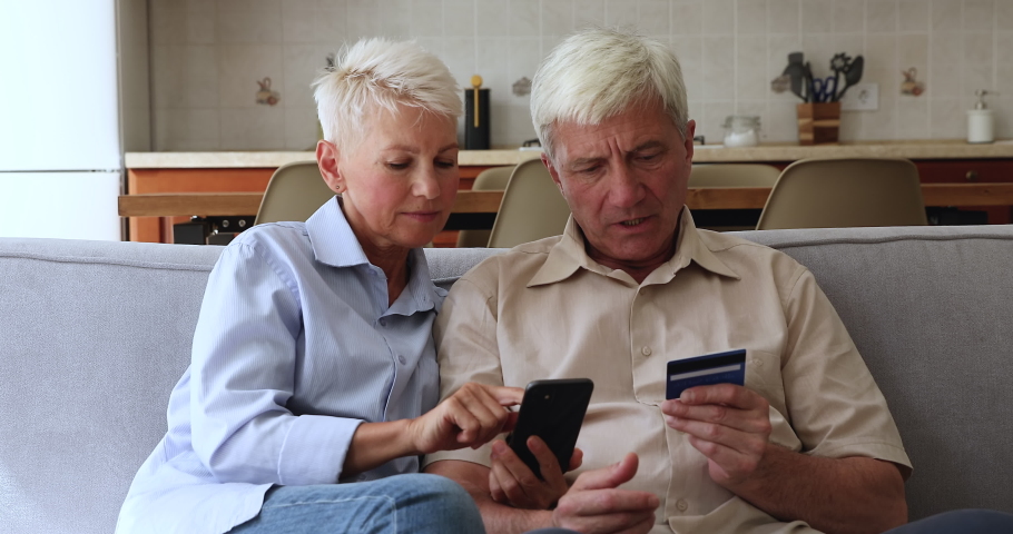 Older spouses holding smartphone feels stressed experiences troubles with ecommerce account or debit card. Fraud and scam, insufficient funds, lack of money, unable unsuccessful online payment concept Royalty-Free Stock Footage #1086932954