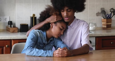 African teenagers 18s couple sit indoors, older brother calming his younger sister, hugs, express sympathy, speaks words of encouragement, provide help. Best friends, support, empathy, bond concept