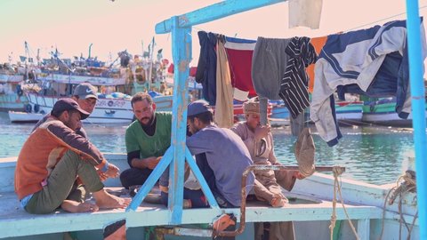 Egypt, Hurghada, 20 DECEMBER 2021: group of fishermen have dinner together after work on a traditional blue fishing boat in an Egyptian harbor. 